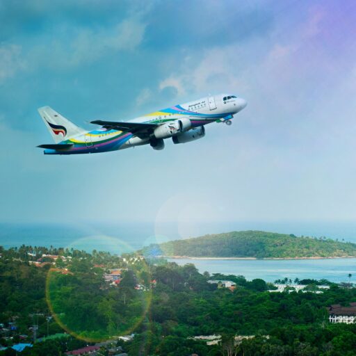 Airplane soaring over Koh Samui island, Thailand, showcasing a vibrant tropical landscape in daylight.